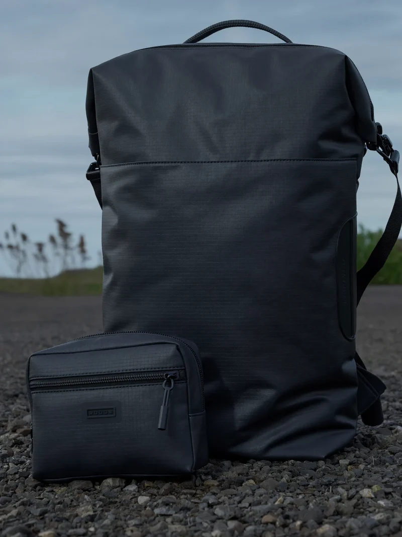 Wasserabweisender Roll-Top-Rucksack mit kleinem Kabel-Organizer auf einem Kiesweg